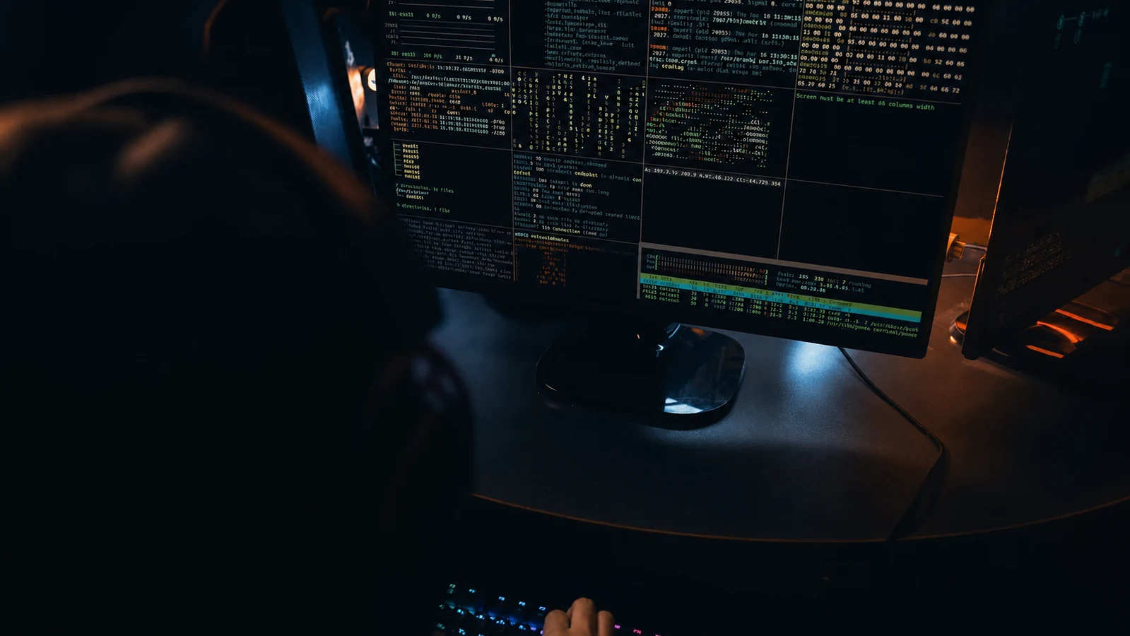 Cybersecurity professional working across computer monitors