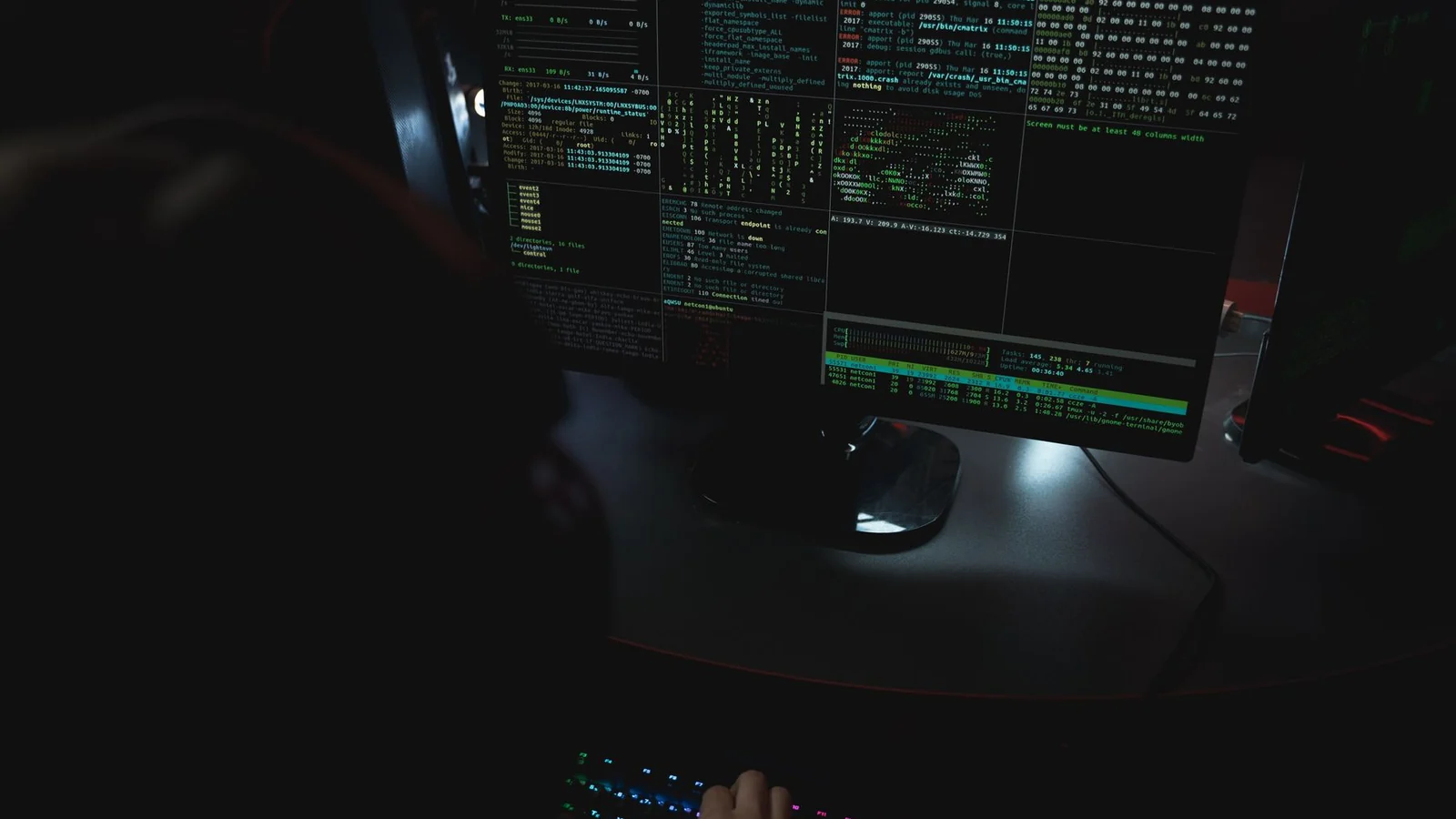 Cybersecurity professional working across computer monitors